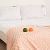 Zwei Igelbälle, ein grüner und ein orangefarbener, liegen auf einem Bett.