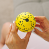 Person hält gelben Faszienball, geeignet für Massage und Muskelentspannung.